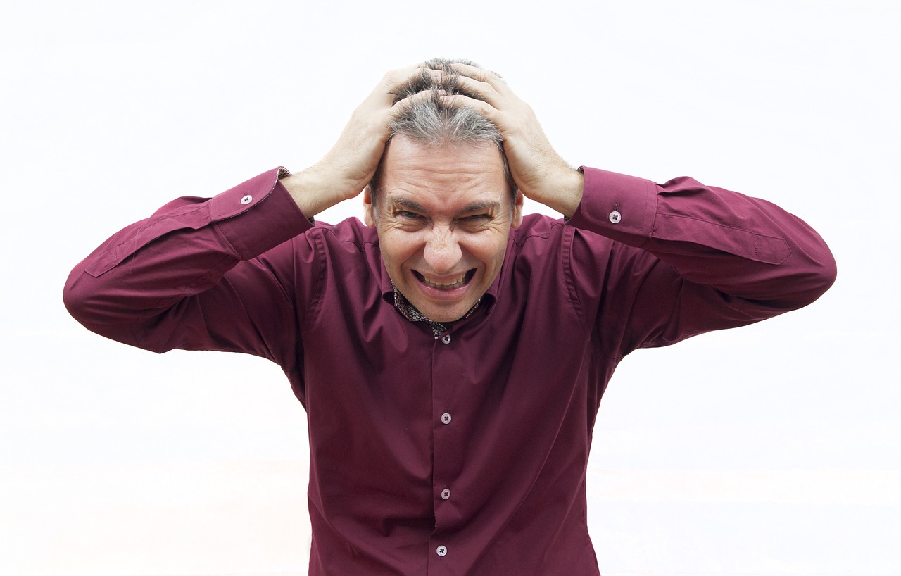 A stressed individual has his hands to his head.